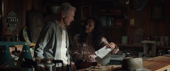 Movie still from “Cry Macho” (2021), directed by Clint Eastwood – An older man and a younger woman looking at a piece of paper; Medium shot, Low angle