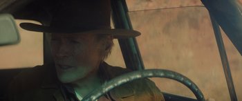 Movie still from “Cry Macho” (2021), directed by Clint Eastwood – A man wearing a hat sitting in the driver's seat of a car; Close Up shot, Low angle