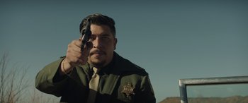 Movie still from “Cry Macho” (2021), directed by Clint Eastwood – A man holding a gun pointed to the sky; Medium shot, Low angle