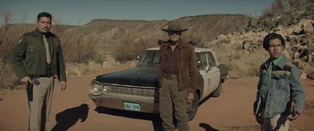 Movie still from “Cry Macho” (2021), directed by Clint Eastwood – An older man standing in front of an old car in the desert; Wide shot, Low angle