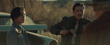 Movie still from “Cry Macho” (2021), directed by Clint Eastwood – A man standing next to an old green car; Medium shot, Over the shoulder angle