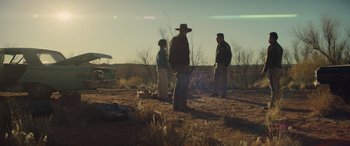 Movie still from “Cry Macho” (2021), directed by Clint Eastwood – A group of men standing on top of a dry grass field; Wide shot, Low angle