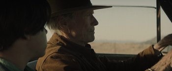 Movie still from “Cry Macho” (2021), directed by Clint Eastwood – An older man wearing a hat looking out a window; Close Up shot, Over the shoulder angle