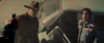 Movie still from “Cry Macho” (2021), directed by Clint Eastwood – A man in a hat and a hat stand in front of an airplane; Medium shot, Low angle