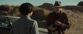 Movie still from “Cry Macho” (2021), directed by Clint Eastwood – A man wearing a hat talking to another man; Medium shot, Over the shoulder angle