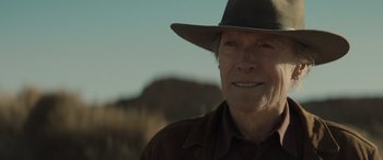 Movie still from “Cry Macho” (2021), directed by Clint Eastwood – An older man wearing a brown hat and a brown jacket; Close Up shot, Over the shoulder angle