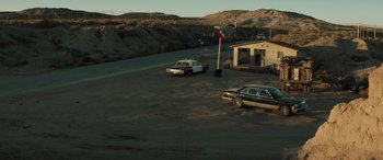 Movie still from “Cry Macho” (2021), directed by Clint Eastwood – A car parked in a parking lot next to a building; Extreme Wide shot, High angle