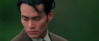Movie still from “Crying Freeman” (1995), directed by Christophe Gans – A person wearing a suit and tie; Close Up shot, Low angle