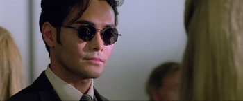 Movie still from “Crying Freeman” (1995), directed by Christophe Gans – A person wearing a suit and sunglasses; Close Up shot, Low angle