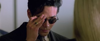 Movie still from “Crying Freeman” (1995), directed by Christophe Gans – A person wearing a suit and sunglasses; Close Up shot, Low angle