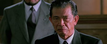 Movie still from “Crying Freeman” (1995), directed by Christophe Gans – An older man wearing a suit and tie; Close Up shot, Low angle