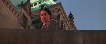 Movie still from “Crying Freeman” (1995), directed by Christophe Gans – A man standing in front of an old building; Close Up shot, Low angle