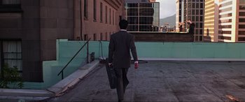 Movie still from “Crying Freeman” (1995), directed by Christophe Gans – A man in a suit walking down a street; Extreme Wide shot, High angle