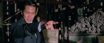 Movie still from “Crying Freeman” (1995), directed by Christophe Gans – A man in a suit pointing to the side; Close Up shot, Low angle