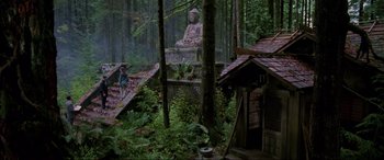 Movie still from “Crying Freeman” (1995), directed by Christophe Gans – A statue of a buddha in the middle of a forest; Extreme Wide shot, Low angle