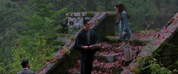 Movie still from “Crying Freeman” (1995), directed by Christophe Gans – A man and a woman standing in a wooded area; Wide shot, Over the shoulder angle