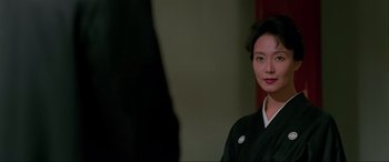 Movie still from “Crying Freeman” (1995), directed by Christophe Gans – A woman in a black kimono is posing for a picture; Close Up shot, Over the shoulder angle