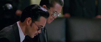 Movie still from “Crying Freeman” (1995), directed by Christophe Gans – A man with glasses is looking at a computer screen; Close Up shot, Low angle