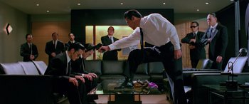 Movie still from “Crying Freeman” (1995), directed by Christophe Gans – A group of men in suits and ties sitting around a coffee table; Medium shot, Low angle