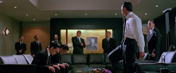 Movie still from “Crying Freeman” (1995), directed by Christophe Gans – A group of men in suits in a living room; Medium shot, Low angle
