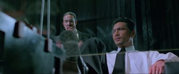 Movie still from “Crying Freeman” (1995), directed by Christophe Gans – Two men in suits and ties sitting next to each other; Medium shot, Low angle