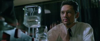 Movie still from “Crying Freeman” (1995), directed by Christophe Gans – A person sitting at a table; Close Up shot, Low angle