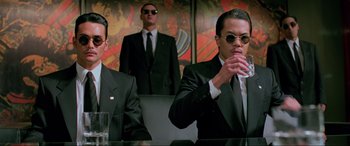 Movie still from “Crying Freeman” (1995), directed by Christophe Gans – A group of men in suits and ties sitting at a table; Medium shot, Low angle