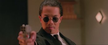 Movie still from “Crying Freeman” (1995), directed by Christophe Gans – A person wearing a suit and sunglasses; Close Up shot, Low angle