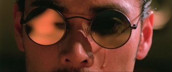 Movie still from “Crying Freeman” (1995), directed by Christophe Gans – A person wearing round glasses; Extreme Close Up shot, Low angle