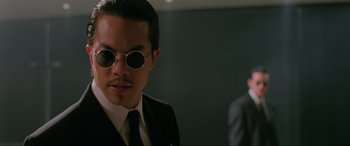 Movie still from “Crying Freeman” (1995), directed by Christophe Gans – A man in a suit and tie wearing sunglasses; Close Up shot, Low angle