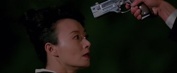 Movie still from “Crying Freeman” (1995), directed by Christophe Gans – A man with a gun pointed at his face; Close Up shot, Over the shoulder angle