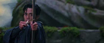 Movie still from “Crying Freeman” (1995), directed by Christophe Gans – A man holding a bow and arrow while standing outside; Close Up shot, Low angle