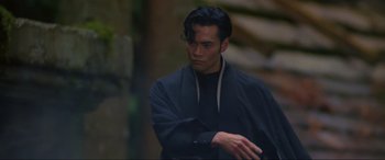 Movie still from “Crying Freeman” (1995), directed by Christophe Gans – A man in a black shirt and a black jacket; Close Up shot, Over the shoulder angle