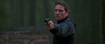 Movie still from “Crying Freeman” (1995), directed by Christophe Gans – A man holding a gun in his right hand; Close Up shot, Over the shoulder angle