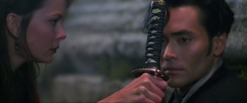 Movie still from “Crying Freeman” (1995), directed by Christophe Gans – A man holding a sword in front of his face; Close Up shot, Low angle