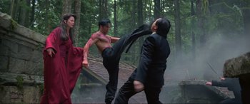 Movie still from “Crying Freeman” (1995), directed by Christophe Gans – A man kicking another man in a forest; Wide shot, Low angle