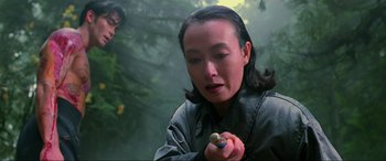 Movie still from “Crying Freeman” (1995), directed by Christophe Gans – A woman holding a small object in her hand; Close Up shot, Over the shoulder angle