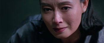 Movie still from “Crying Freeman” (1995), directed by Christophe Gans – A woman's face with a dark background; Close Up shot, Low angle