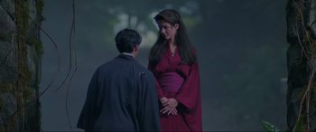 Movie still from “Crying Freeman” (1995), directed by Christophe Gans – A man and a woman standing next to each other in front of a tree; Medium shot, Low angle