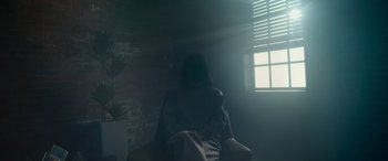 Movie still from “Cyber Hell: Exposing an Internet Horror” (2022), directed by Jin-sung Choi – A person sitting in a chair in a room with a brick wall; Wide shot, Low angle