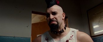 Movie still from “The Wrestler” (2008), directed by Darren Aronofsky – A man with a black mohawk is wearing a white tank top; Close Up shot, Low angle