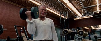Movie still from “The Wrestler” (2008), directed by Darren Aronofsky – An old man holding a weight in a gym; Medium shot, Low angle