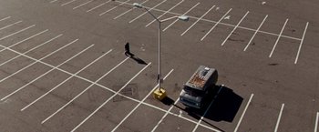 Movie still from “The Wrestler” (2008), directed by Darren Aronofsky – A person walking in a parking lot next to a van; Extreme Wide shot, Overhead angle