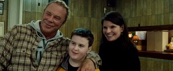 Movie still from “The Wrestler” (2008), directed by Darren Aronofsky – A man and a woman and a young boy are posing for a picture; Close Up shot, Over the shoulder angle
