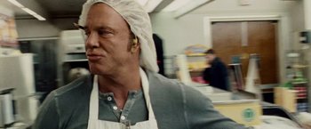 Movie still from “The Wrestler” (2008), directed by Darren Aronofsky – A man wearing an apron and a head covering; Close Up shot, Over the shoulder angle