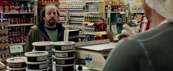 Movie still from “The Wrestler” (2008), directed by Darren Aronofsky – A man is sitting at the counter of a store; Medium shot, Over the shoulder angle