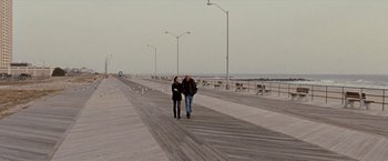 Movie still from “The Wrestler” (2008), directed by Darren Aronofsky – Two people are walking on a boardwalk near the ocean; Wide shot, High angle