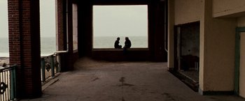Movie still from “The Wrestler” (2008), directed by Darren Aronofsky – Two people sitting on a ledge looking out at the ocean; Extreme Wide shot, High angle