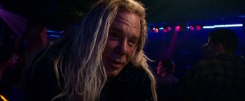 Movie still from “The Wrestler” (2008), directed by Darren Aronofsky – A man with long blonde hair is smiling for the camera; Close Up shot, Low angle