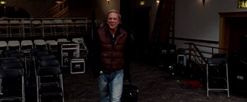 Movie still from “The Wrestler” (2008), directed by Darren Aronofsky – A man in a brown vest standing next to some luggage; Medium shot, Over the shoulder angle